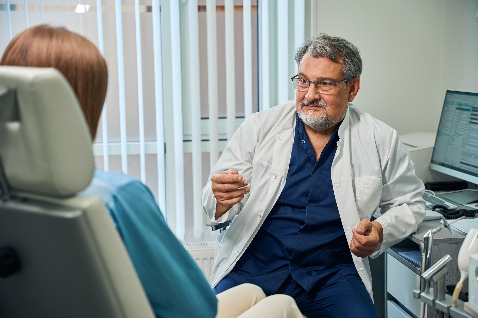 Elderly doctor gesturing during patient consultation